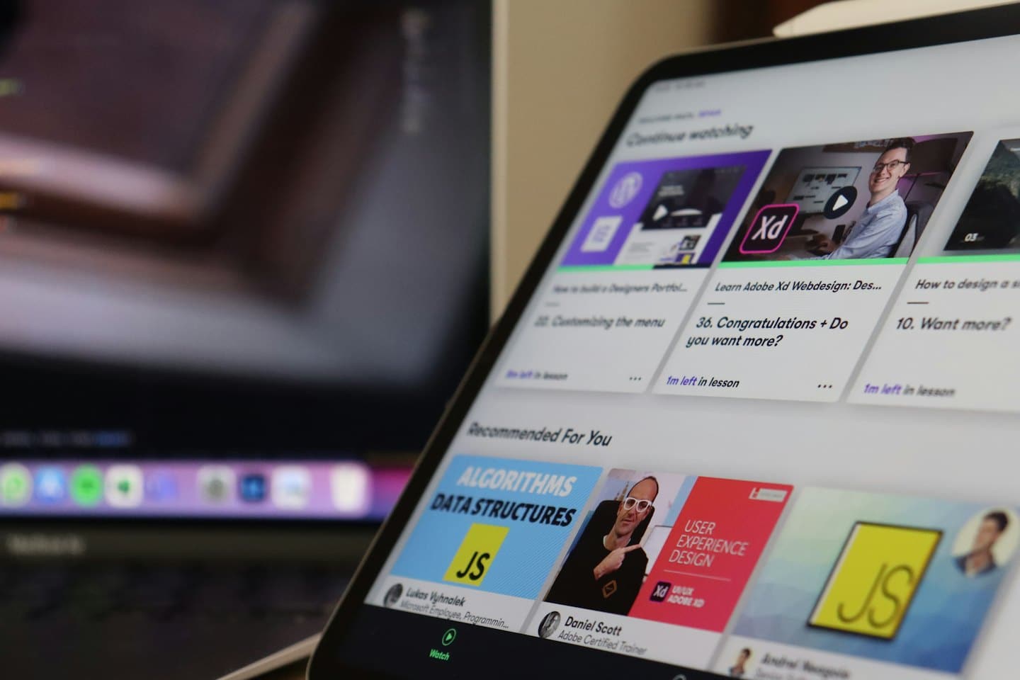 Ein Tablet zeigt eine Online-Lernplattform mit Kurs-Thumbnails.